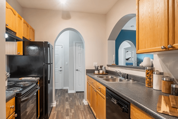 A kitchen with wooden cabinets and a black refrigerator.
